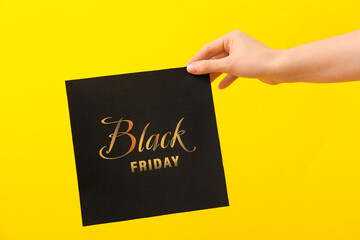 Female hand holding card with text BLACK FRIDAY on color background