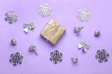 Present with Christmas decor on lilac background