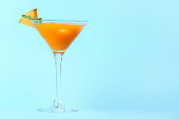 Glass of cold melon cocktail on blue background