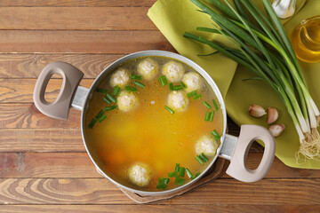 Pot with tasty meatball soup on wooden background