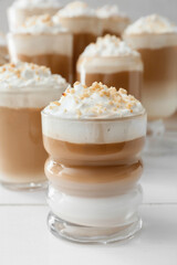 Glasses of tasty latte with nuts on table, closeup