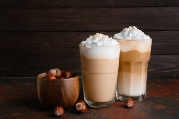 Glasses of tasty latte with nuts on table
