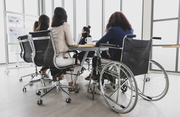 Asian business women and handicap woman sitting on wheelchair are in meeting together on the table in office. Concept for business meeting