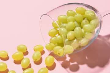 Glass with fresh green grapes on color background, closeup