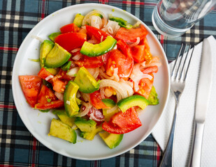 Healthy vegetable salad of sliced fresh tomatoes, avocado and onion with olive oil