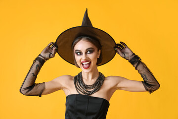 Beautiful young woman in Halloween costume of witch on color background