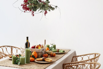 Autumn table setting with fresh pumpkins and leaves near light wall