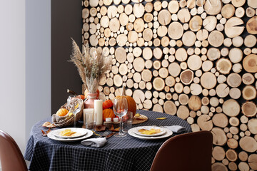 Autumn table setting with fresh pumpkins and leaves near wooden wall