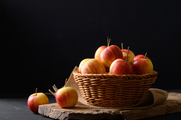 Fresh red apple fruit in a basket on wooden with black background, Still Life