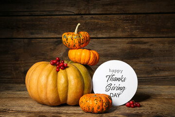 Different pumpkins and text HAPPY THANKSGIVING DAY on wooden background