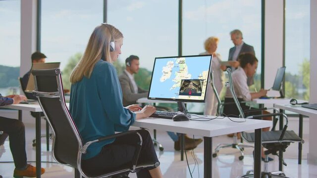 Woman browsing online map on monitor and having videocall with business partner. Modern open space office interior.