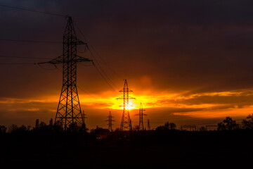 High voltage power line at sunset. Silhouettes of the metal pillars