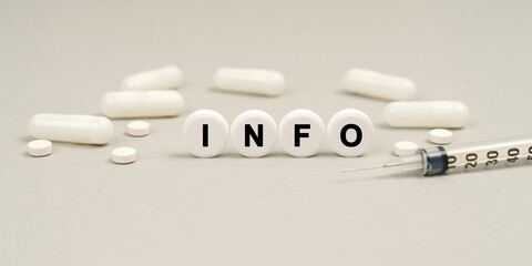 On the table are capsules, a syringe and pills that say - INFO