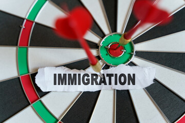 The picture shows a target, darts and a torn piece of paper with the inscription - IMMIGRATION