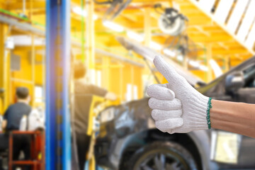 Technician man giving thumb up with car repair service centre blurred background