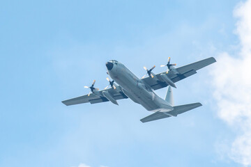 Military transport aircraft conducting training flight in the blue sky background. - obrazy, fototapety, plakaty