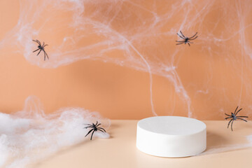 Obraz premium White podium with spider web and spiders on an orange background. product display. Simple modern autumn design