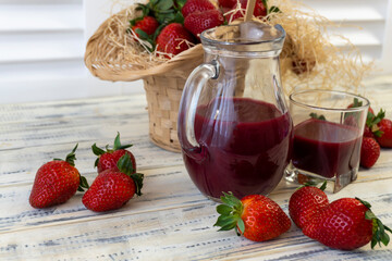 Strawberry in basket and on table on wooden background, strawberry juice in jug