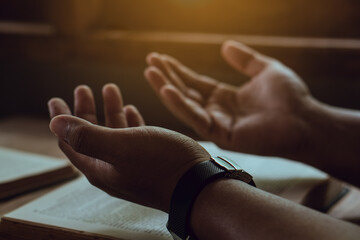 Hands of man with Bible praying.Christian life prayer to god. Man Pray for god.believe in goodness. Holding hands in prayer on a wooden table.