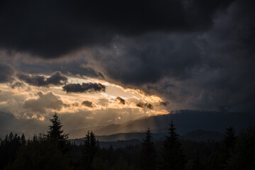 Fototapeta na wymiar Sunbeams going through dark clouds over majestic mountains