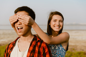 White woman covering his boyfriend's and laughing while hiking outdoors