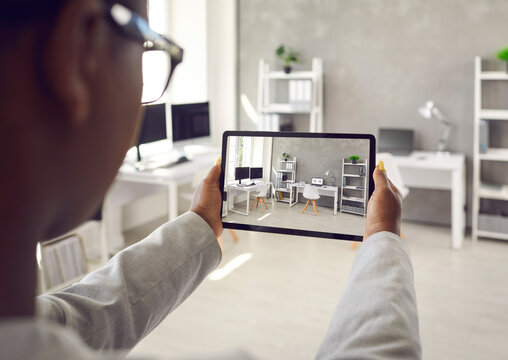 Black rental agent making photo presentation of apartment takes interior snaps using smart tablet device. Realtor shows office workspace while video calling client and giving tour around display home