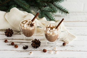 two transparent mugs with a double bottom with hot chocolate and marshmallow on a white wooden background. the concept New Year holidays.