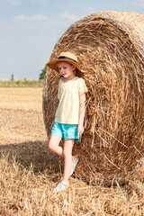 Naklejka na ściany i meble Little girl having fun in a wheat field on a summer day.