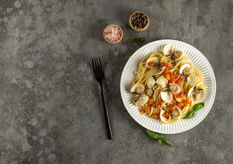 Tasty appetizing fresh homemade clams alle vongole seafood pasta with tomatoes, garlic, and white wine on the plate. top view, copy space.