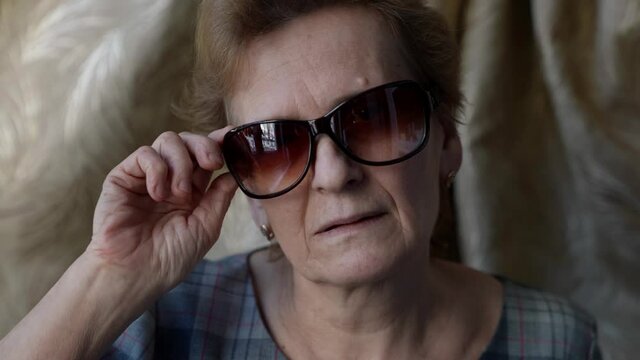 retiree woman is putting on and off sunglasses, protection for eyes in sunny day
