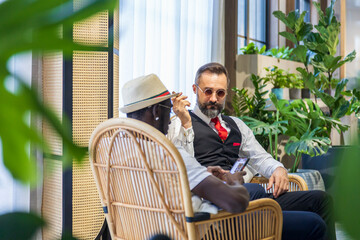 Caucasian businessman in formal wear and his African American friend in luxury tropical style hotel...