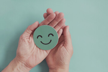 Hands holding green happy smile face paper cut, good feedback rating,positive customer review, experience, satisfaction survey ,mental health assessment, child wellness,world mental health day concept - obrazy, fototapety, plakaty