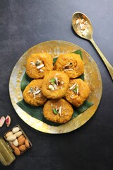 Indian traditional sweet balushahi served on a metal plate over black background. Also known as Balsaahi, badushah is a sweet food served on a Brass plate over moody background. Copy space.