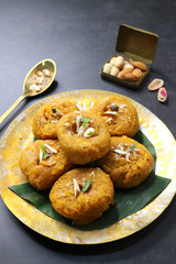 Indian traditional sweet balushahi served on a metal plate over black background. Also known as...