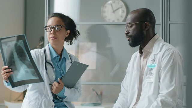 Mixed race female doctor and her African American male colleague discussing chest x ray image while working together in clinic