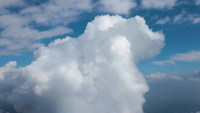 Aerial view from airplane window at high altitude of earth covered with white puffy cumulus clouds.
