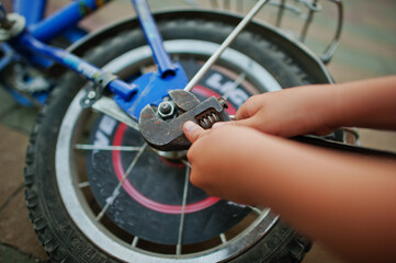 Fototapeta na wymiar Boy hands repair bike. Little mechanic work with bicycle.