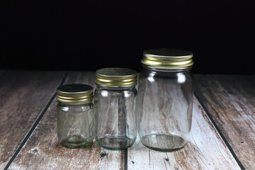 Pile of mixed size bottle glass with metal cap on the wooden background.