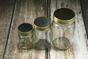 Pile of mixed size bottle glass with metal cap on the wooden background.