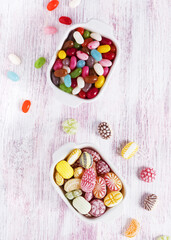 Two white ceramic bowls with colorful candies and jelly beans. Top view.