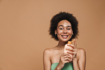 Black brunette woman smiling while posing with beauty product