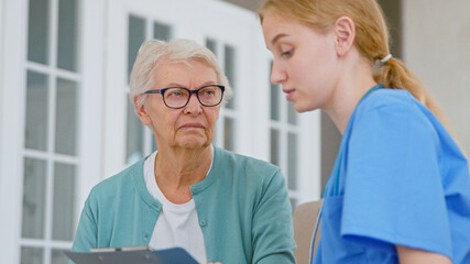 Young doctor shows test results on clipboard to doubting senior patient in light office
