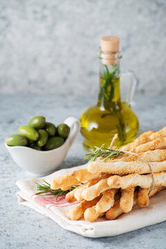 Traditional Italian snack grissini-breadsticks with olive oil and sesame seeds on a light background