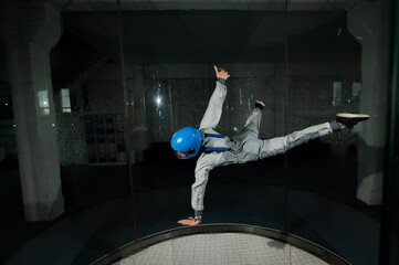 A young woman in overalls and a protective helmet enjoys flying in a wind tunnel. Free fall simulator