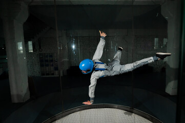 A young woman in overalls and a protective helmet enjoys flying in a wind tunnel. Free fall...