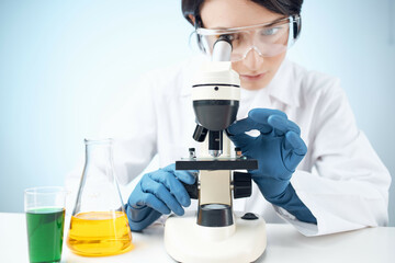 Fototapeta premium woman looking through a microscope chemical solution laboratory research biotechnology
