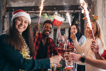 Multi-ethnic friends toasting wine. Young men and women having a party in cafe. Christmas