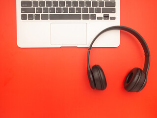 Top view of headphones over on a laptop isolated on a red background with space for text. Technology and relaxation concept