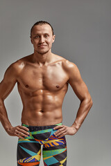 Fototapeta premium Portrait of a swimmer half-length portrait, young athlete swimmer in suit for swimming, copies of space, gray background. Motivation, advertising banner, place for text