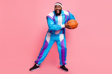 Full length photo of young african man happy positive smile play basketball competition isolated over pink color background